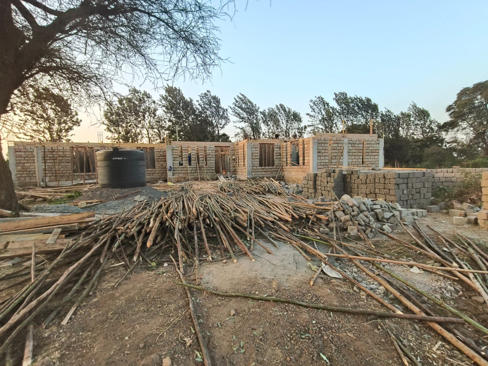 Near-complete house with block walls and water tank at dusk