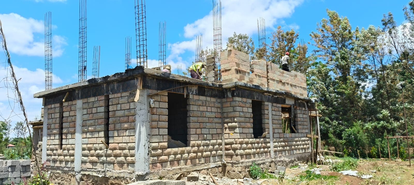Workers building up rooftop columns on a block wall house