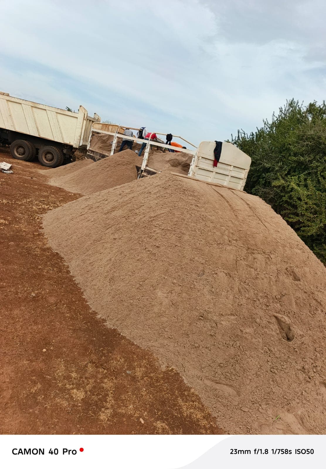 Sand piles being offloaded between two tipper trucks