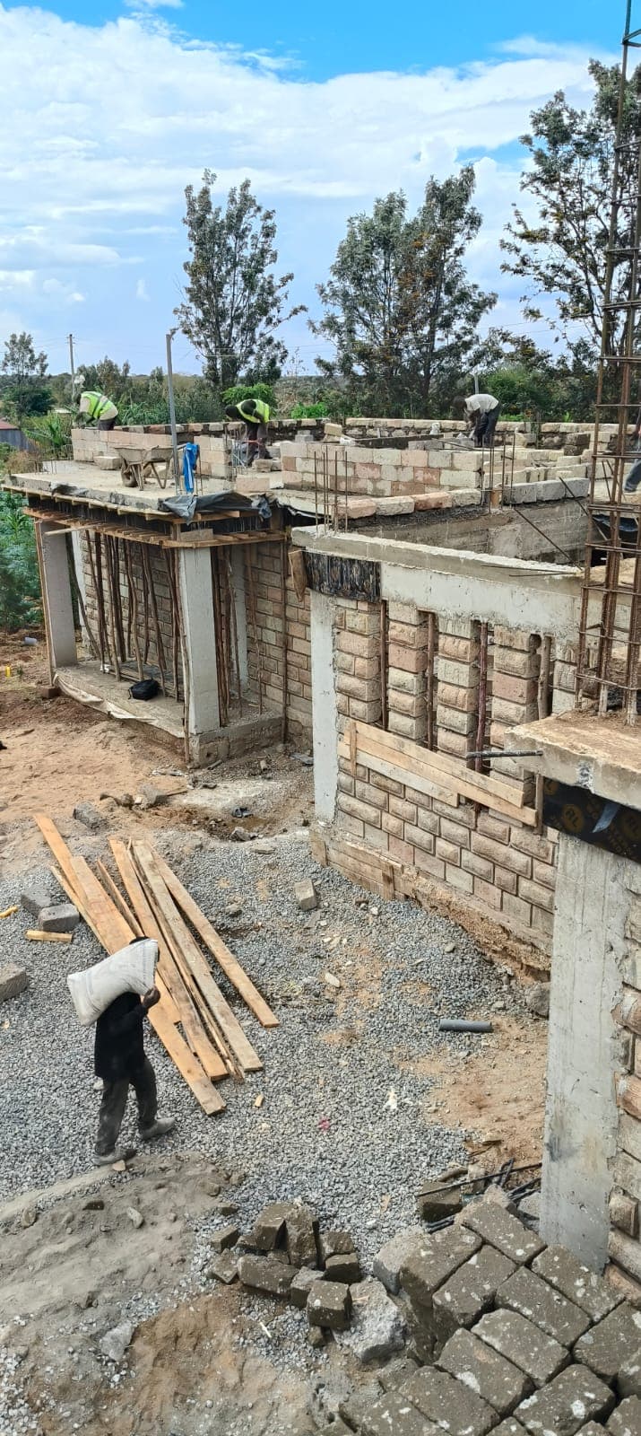 Worker carrying materials across a block wall building site