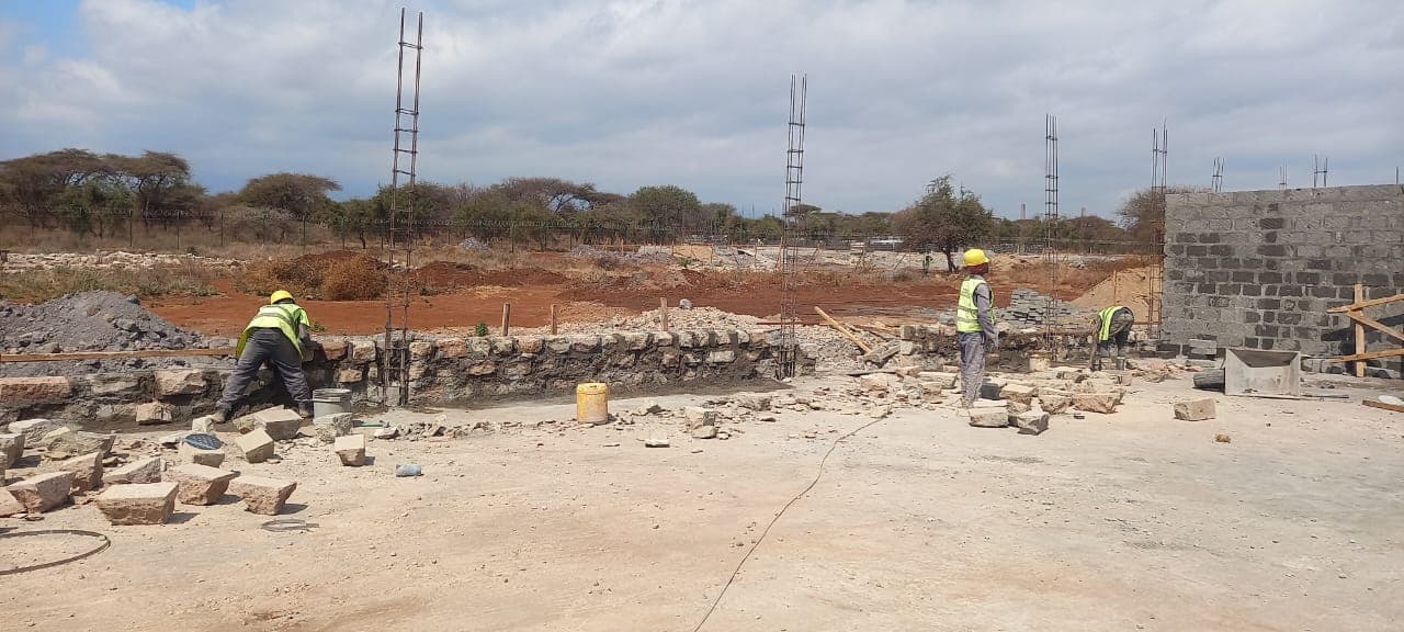 Mason laying a stone foundation wall on site