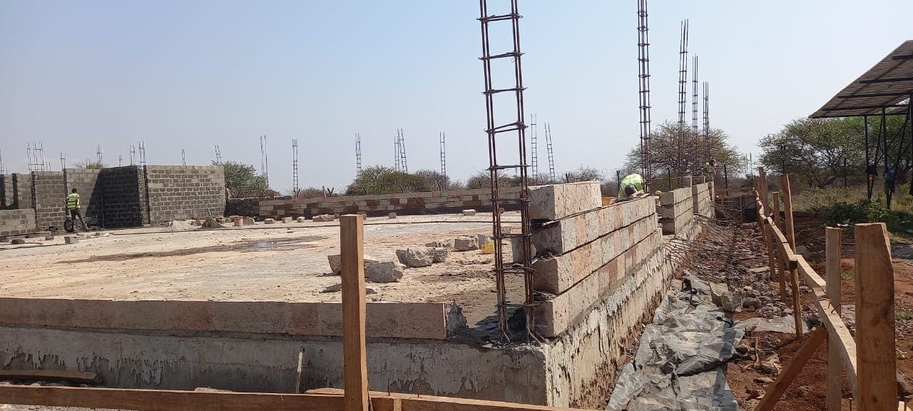 Workers laying blockwork on a rising building foundation